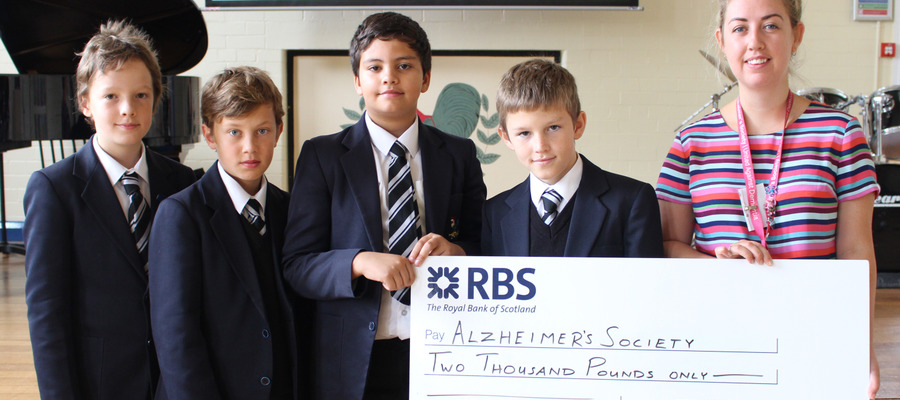 Bolton School Junior Boys present a cheque for £2000 to Alzheimer’s Society’s Stephanie Potts, Community Fundraiser for Greater Manchester
