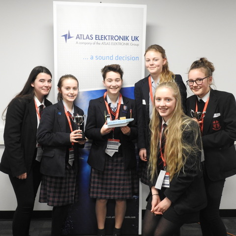 Talbot Heath and All Saints pupils smiling proudly with their winning STEALTH boat and trophies.